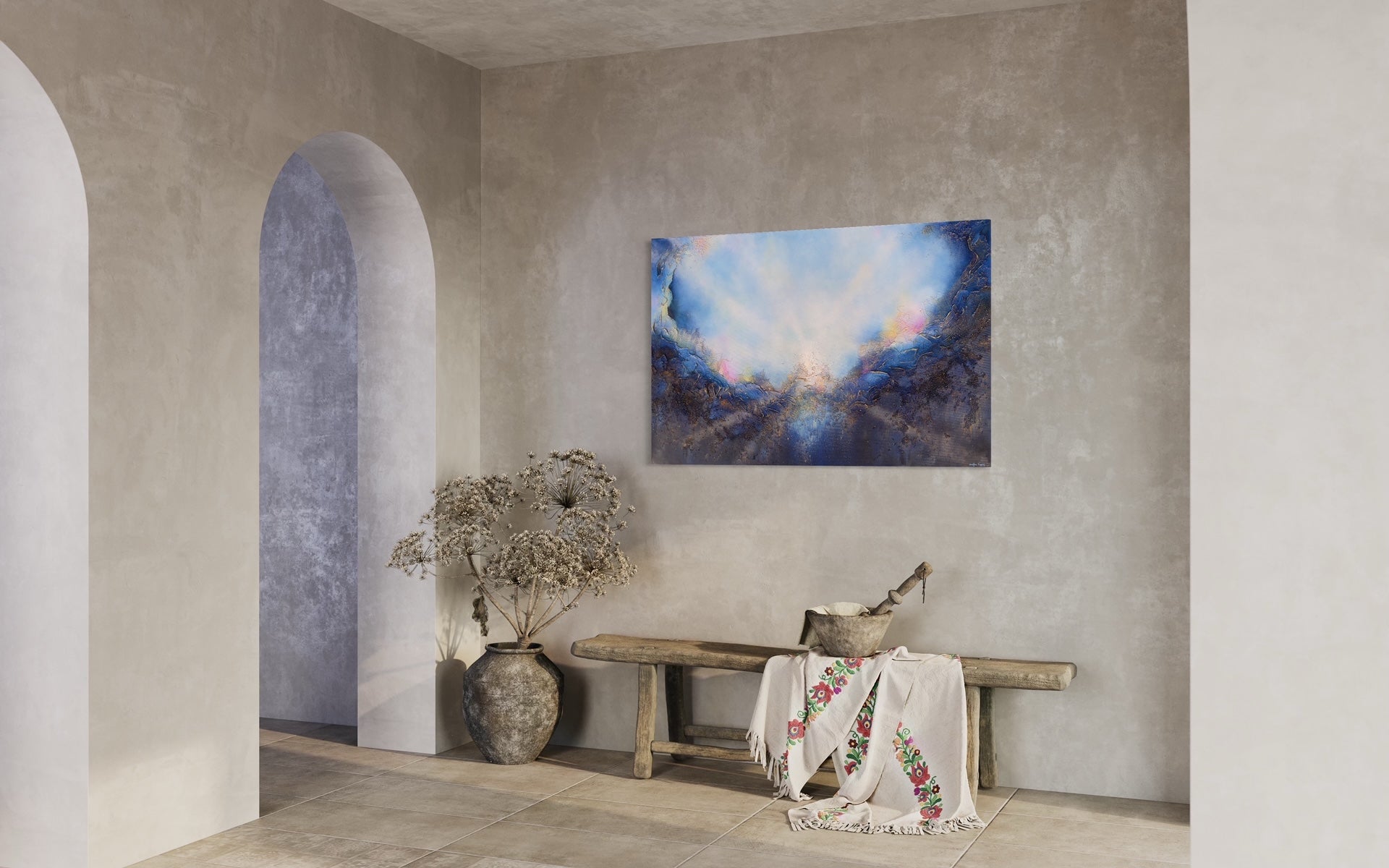Soul's Return, hanging over a rustic wood bench with dried plants, in an entry with rounded doorways and stone walls. a textured painting with light rays shining out from the center representing the soul's return to one's self, or the universe. Blue, pink, white, dark blue, textured painting. Ephemeral art, art with meaning, soul artist. Jennifer Tepper Fine Art.